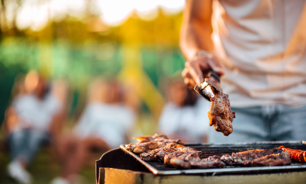 Close-up image of man barbecuing meat on the grill outdoors.