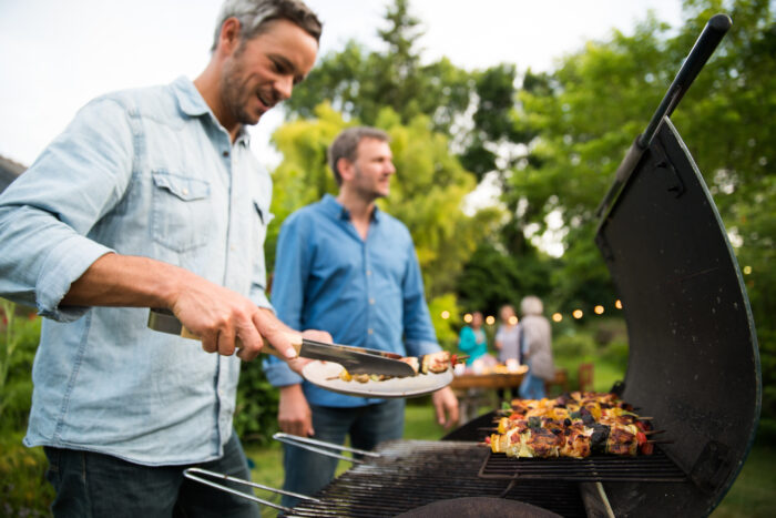 in a summer evening,  two men  in their forties prepares a barbe