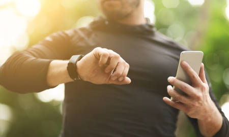 Man checking data on fitness tracker after training outdoors