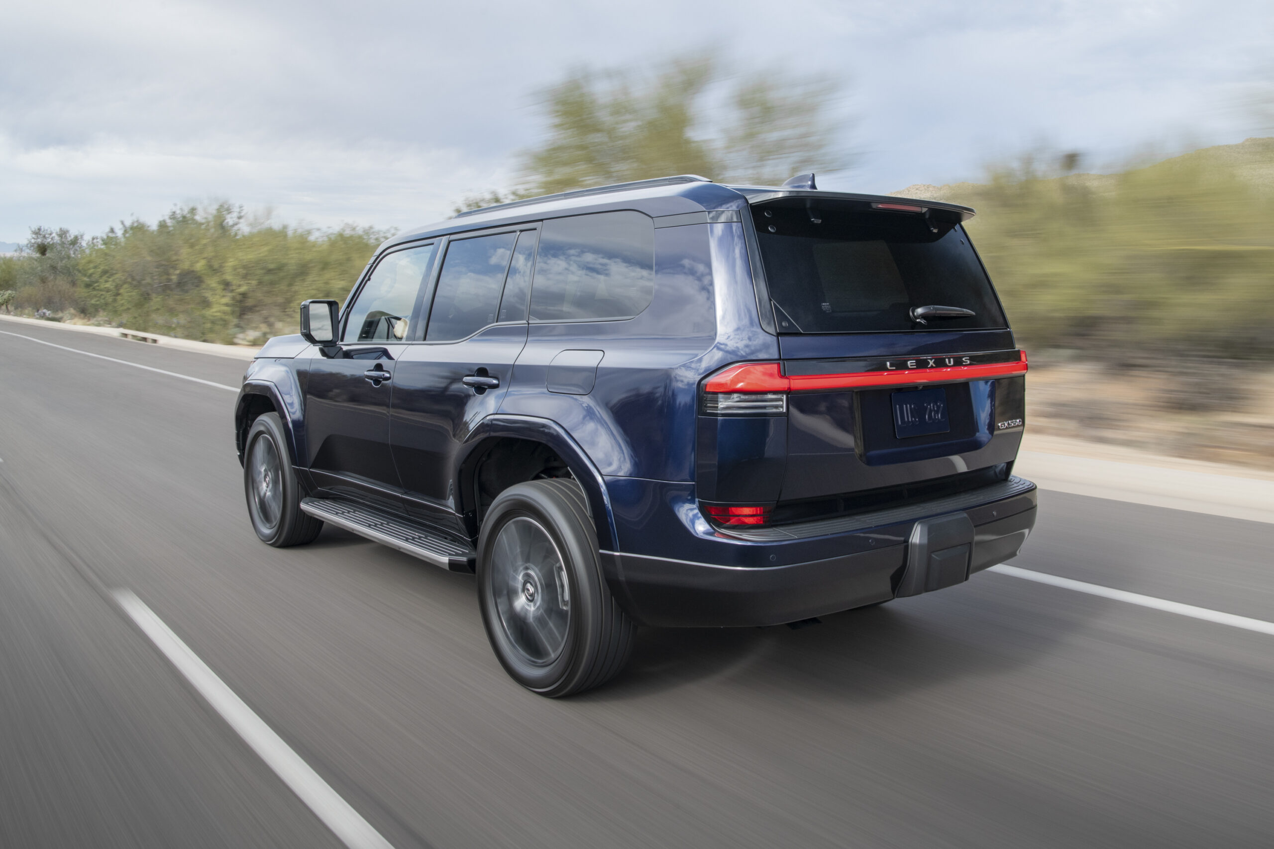 The GX 550 seen from the rear while driving on a paved desert road.